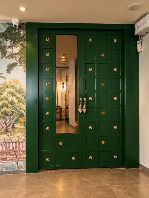 Telugu Theory entrance: a green panelled double door with brass studs beside a painted mural