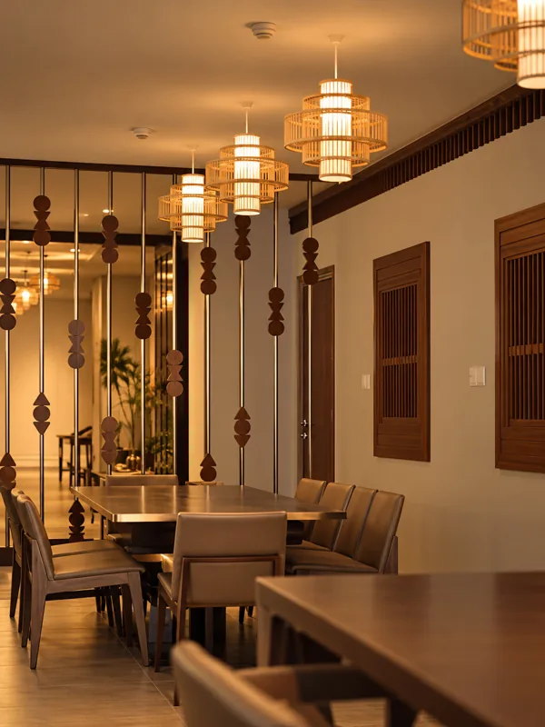 Private dining table behind a screen of hanging wooden beads, with woven pendant lamps